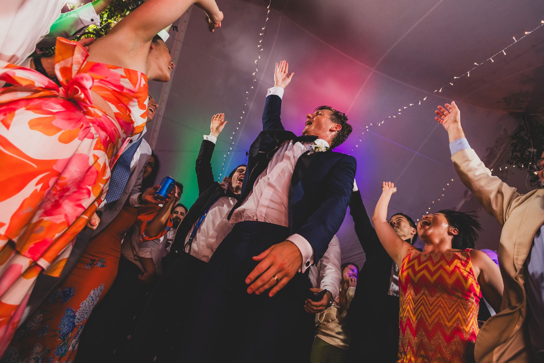 Groom jumping with arms up on the dance floor