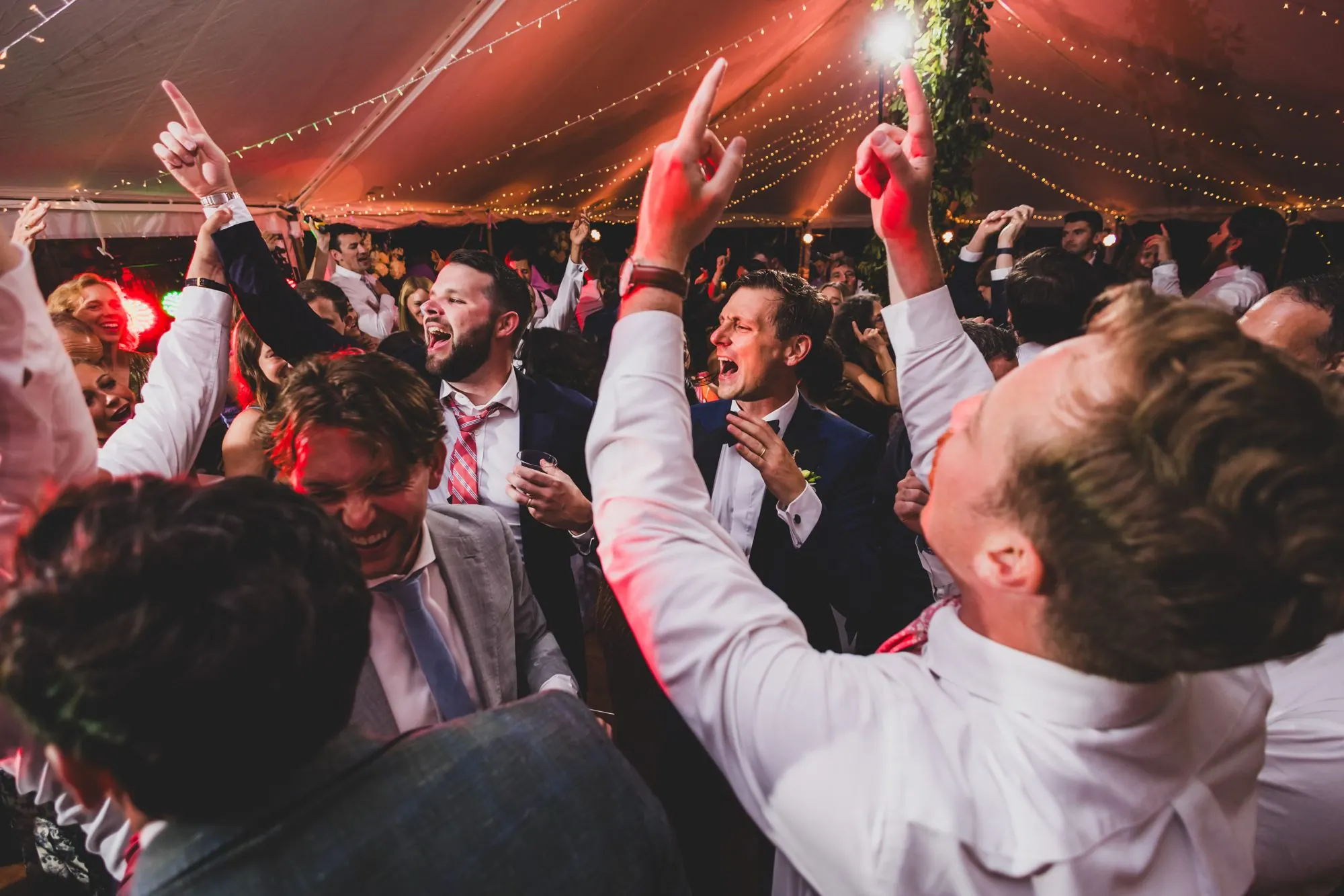 Wedding guests singing along with hands up at the end of the night